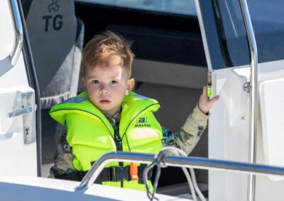Kleines Kind auf Kabinenboot mit Schwimmweste